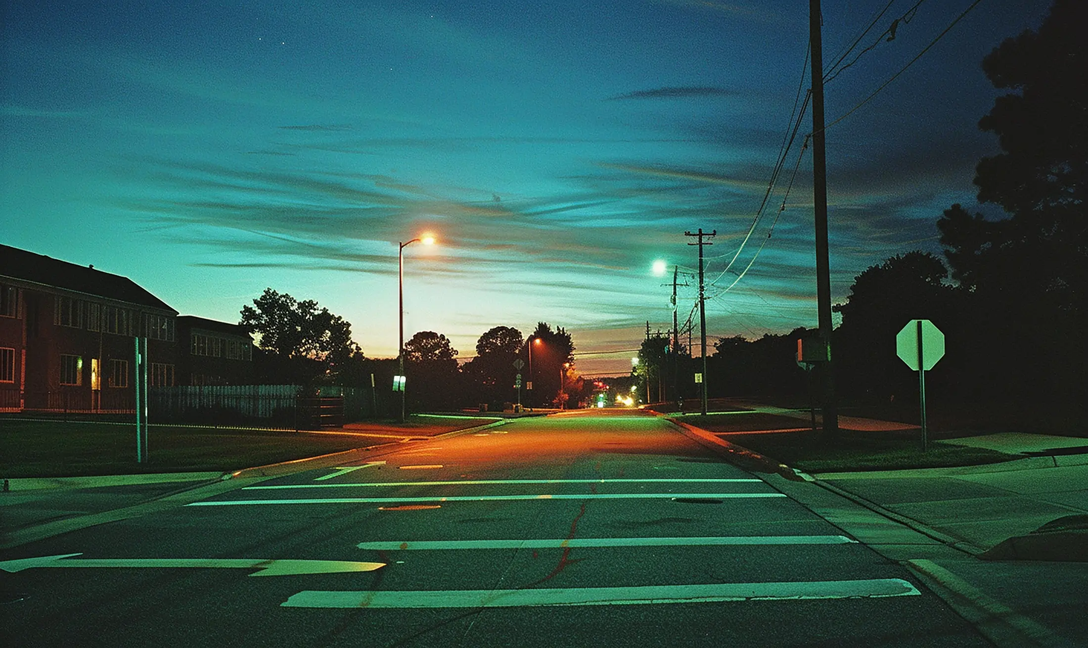 An empty street at dusk with the streetlights just on and nobody about