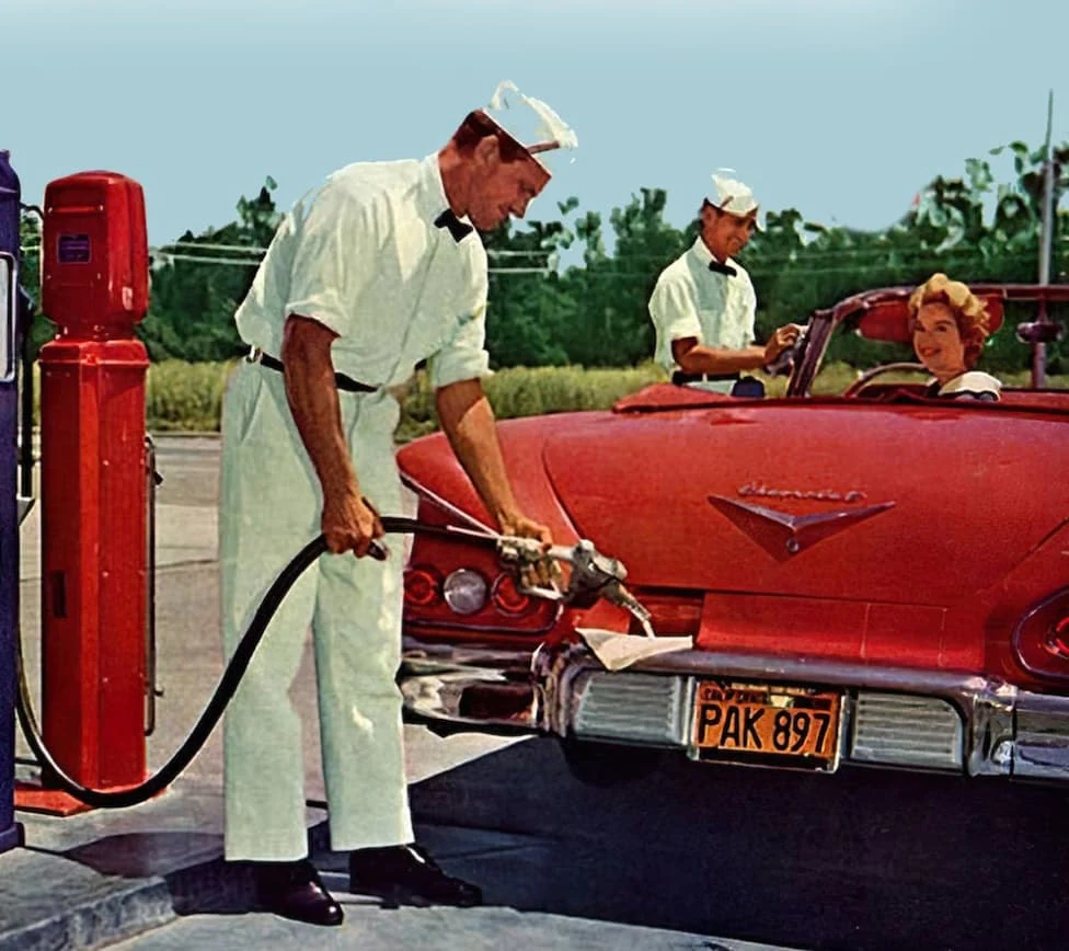 Two uniformed attendants filling and cleaning a car at a 1950s service station