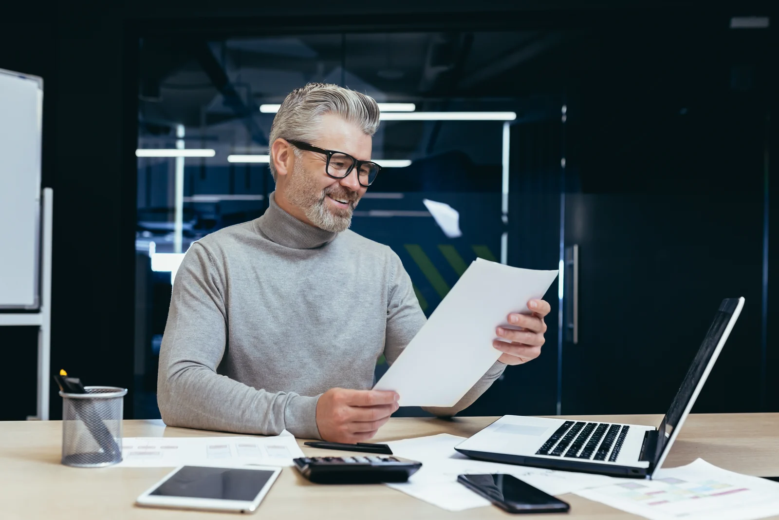 A business owner reading his month on one page, calculator on the desk