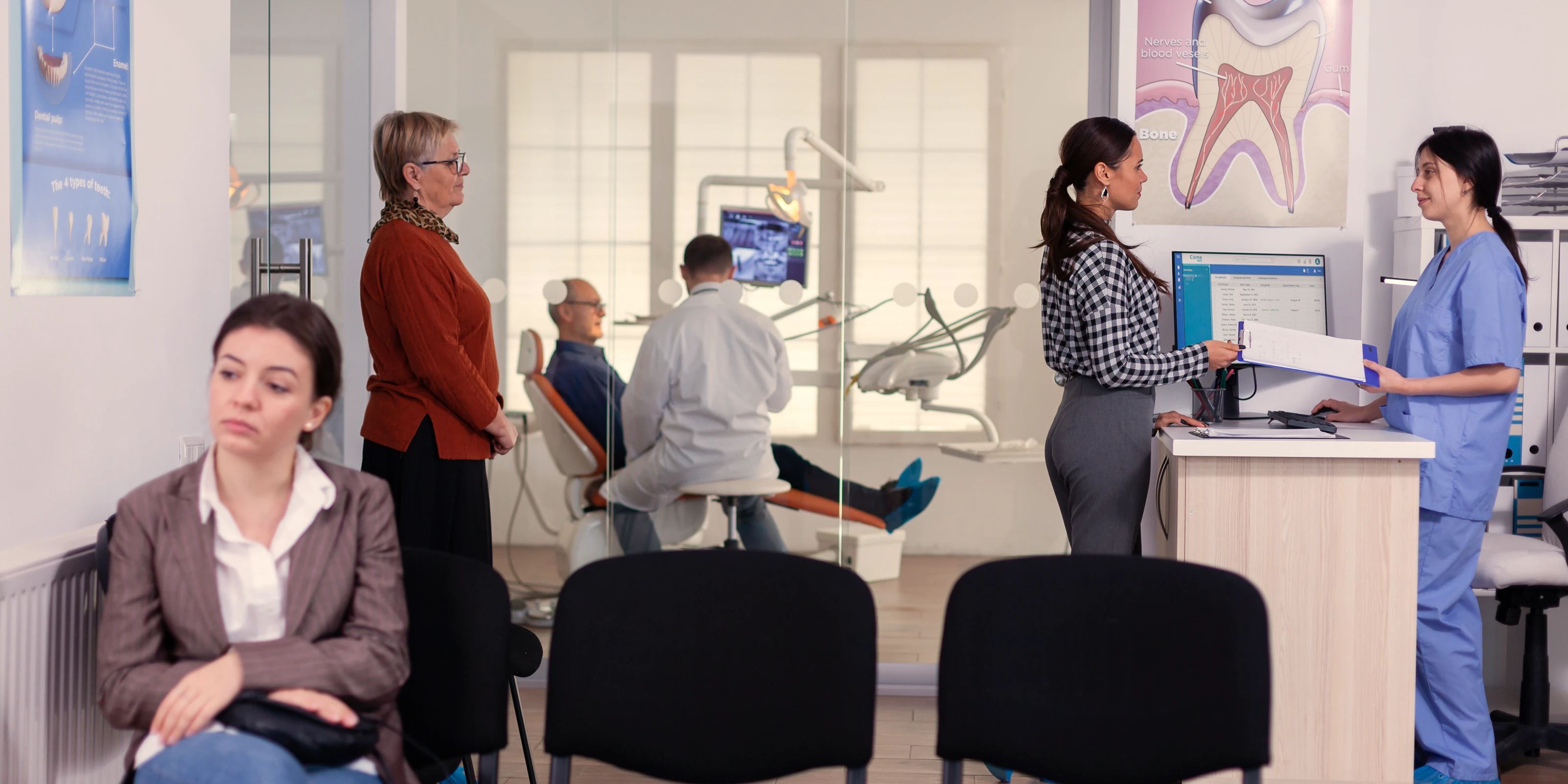 A full waiting room, with the treatment room and the front desk both busy behind it