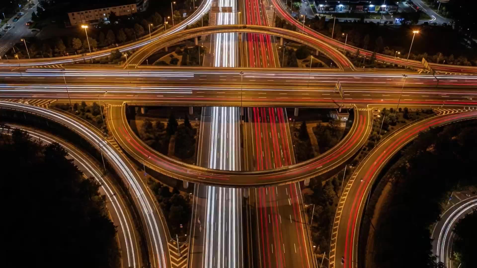 An aerial view of a highway interchange at night with car light trails